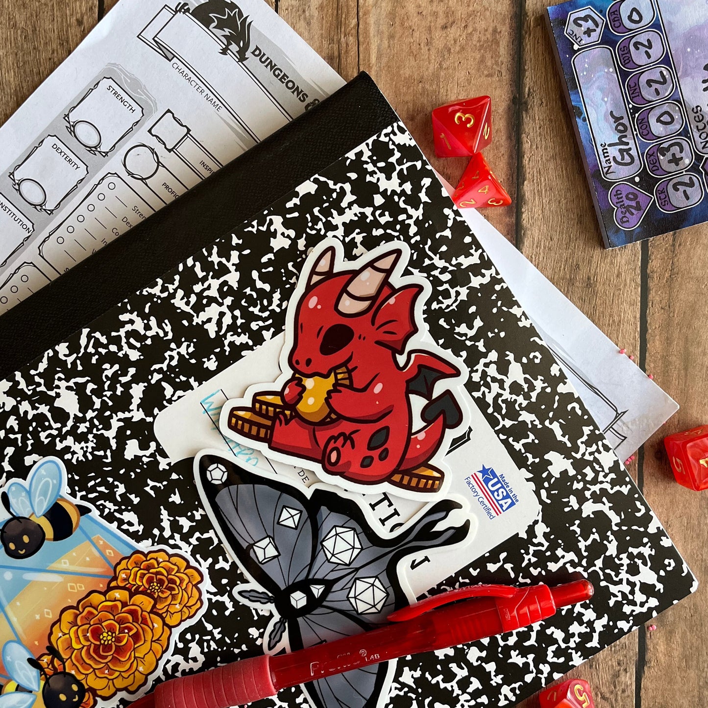 The sticker setup on a note book with other stickers made by the artist on a table setting.